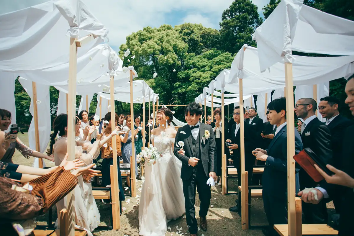 白いテントの下でゲストに祝福される新郎新婦